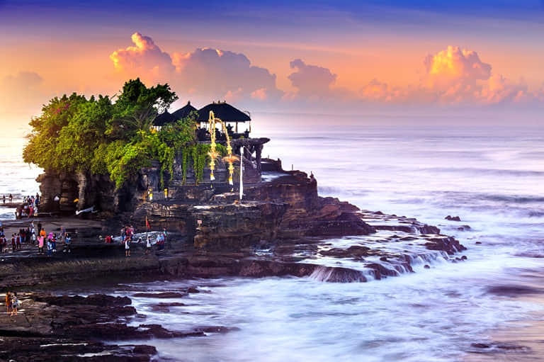 Sacred ocean temple perched over dramatic coastal waves at sunset